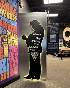 silouette of johnny cash playing his guitar and facing a wall of brightly colored text