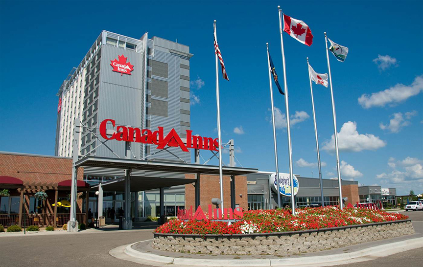 exterior of a hotel with red flowers and flags in front