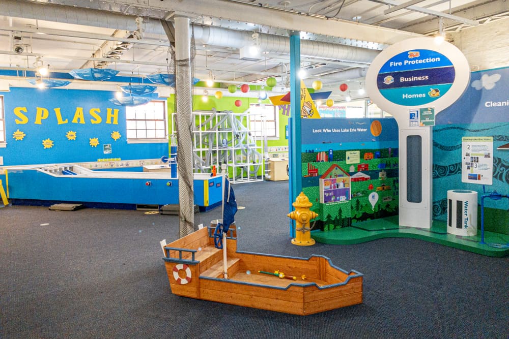 A yellow boat shaped toy box in front of yellow fire hydrant inside children's museum