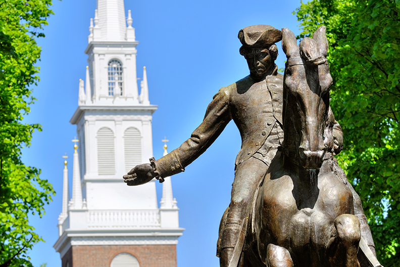 stature of Paul Revere sitting on a horse in front of a church steeple