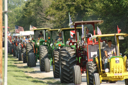 a parade of multiple old farm tractors