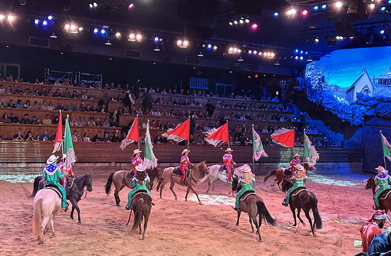 horses and riders holding flags in a circle in the arena