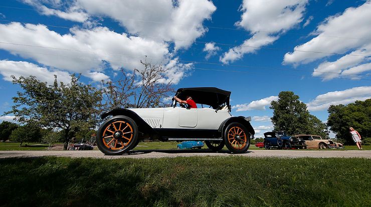 White antique car with blue sky and scattered clouds