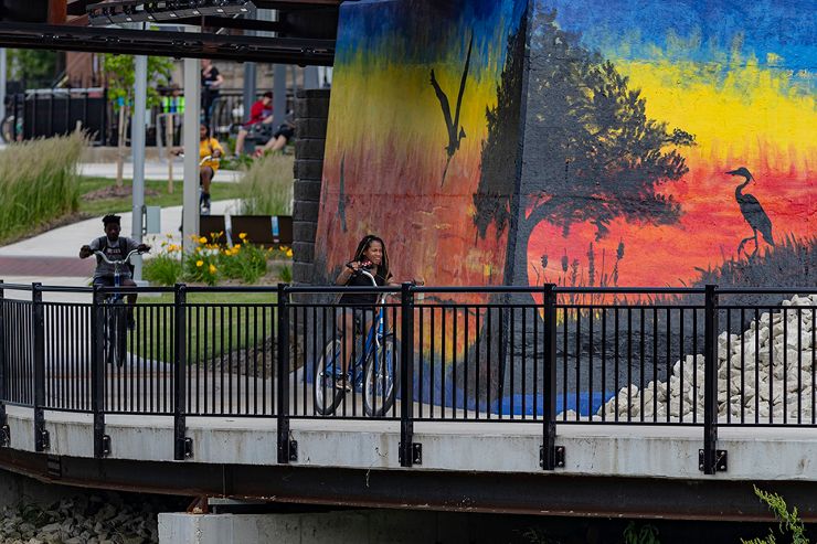 Bike riders on Downtown Kokomo Trails with art mural