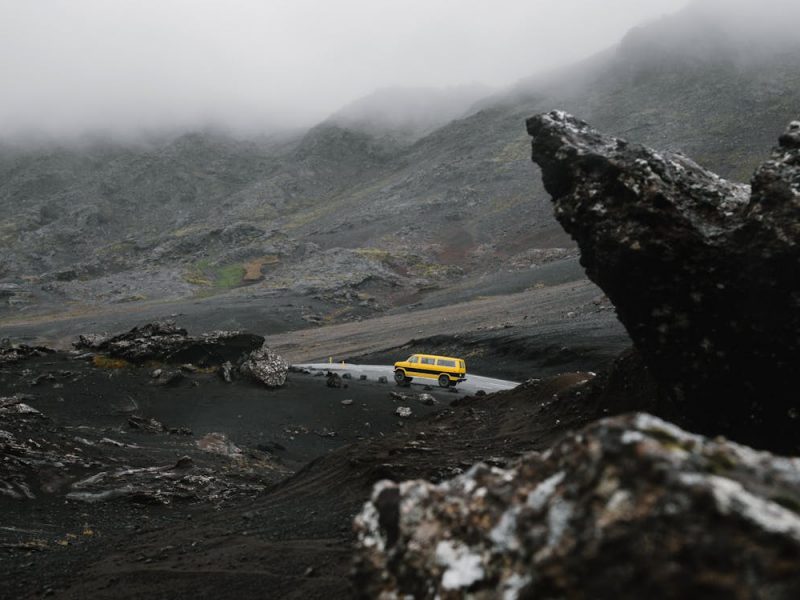 Car driving on road between ridge under overcast sky