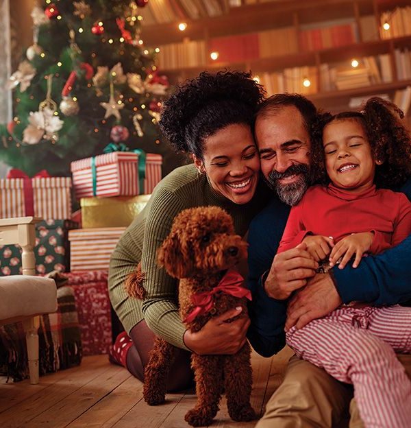 black family in front of christmas tree hugging each other and their dog