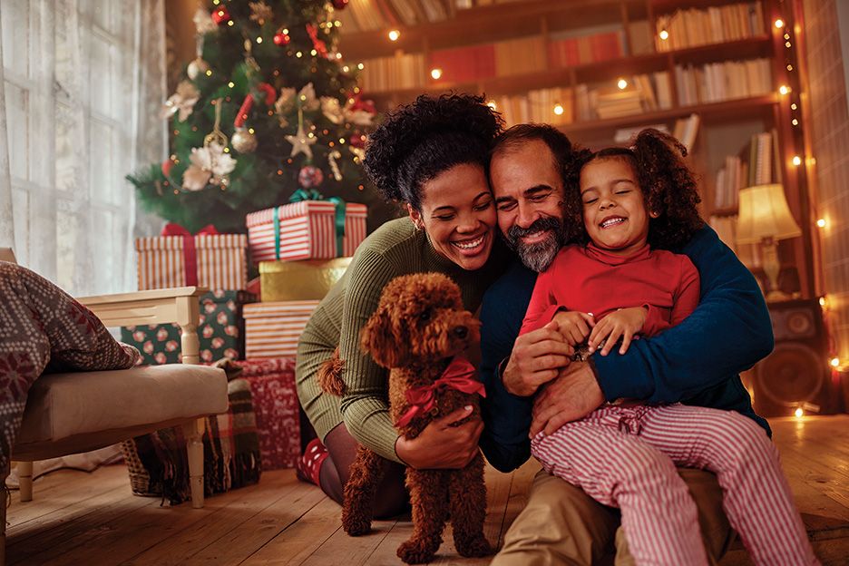 black family in front of christmas tree hugging each other and their dog