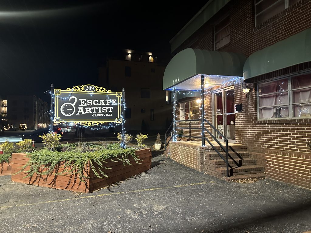 Outside of brick building at Escape-Artist with header signs in the yard