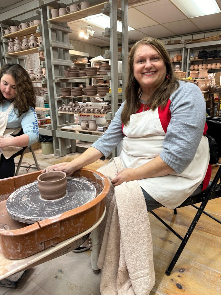 sitting at a potter's wheel to learn how to make pottery