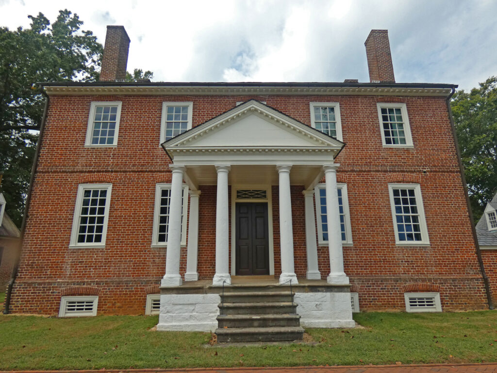 two story brick historical home with white columns in the front center.