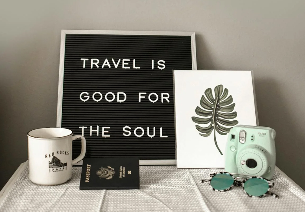 A posterboard on a table that says "Travel is good for the soul." 