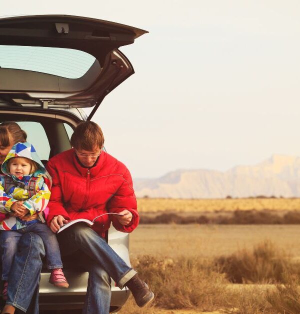 Family with baby sitting in the back liftgate of their car