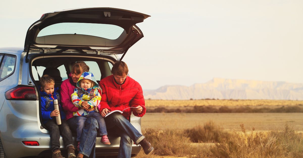 Family with baby sitting in the back liftgate of their car