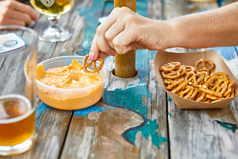 Dipping a pretzel into a bowl of melted cheese