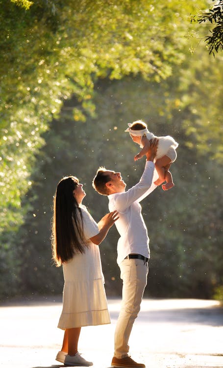 a couple stading outside with the man holding up a baby above his head