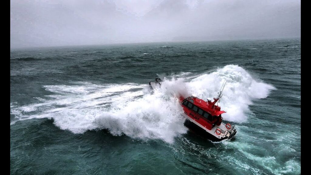 a red boat riding the waves in the ocean