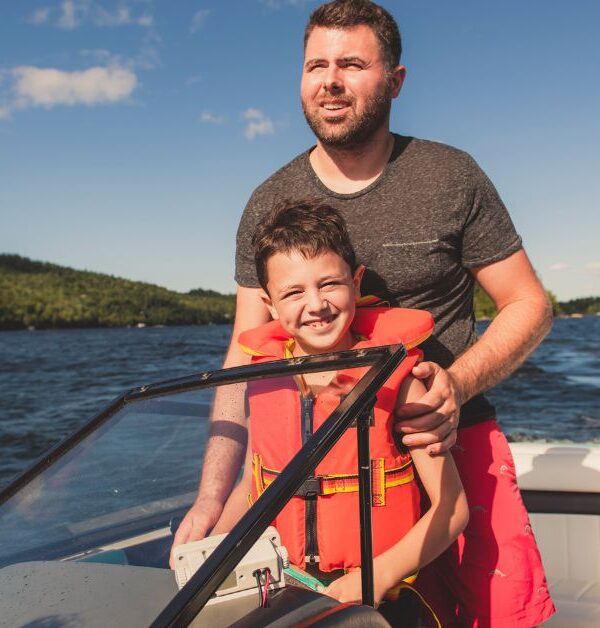 man standing behind his son on a boat on water