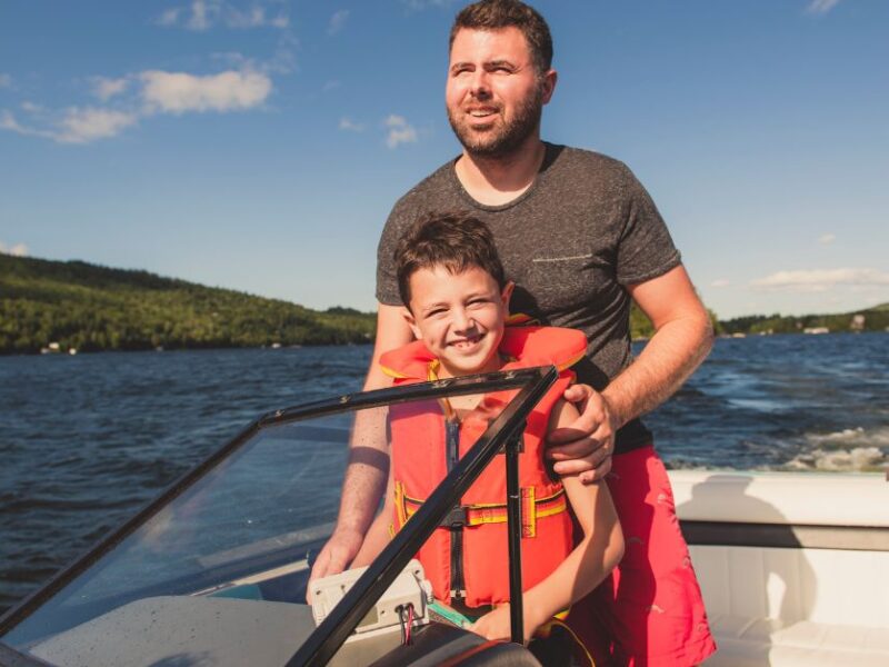 man standing behind his son on a boat on water