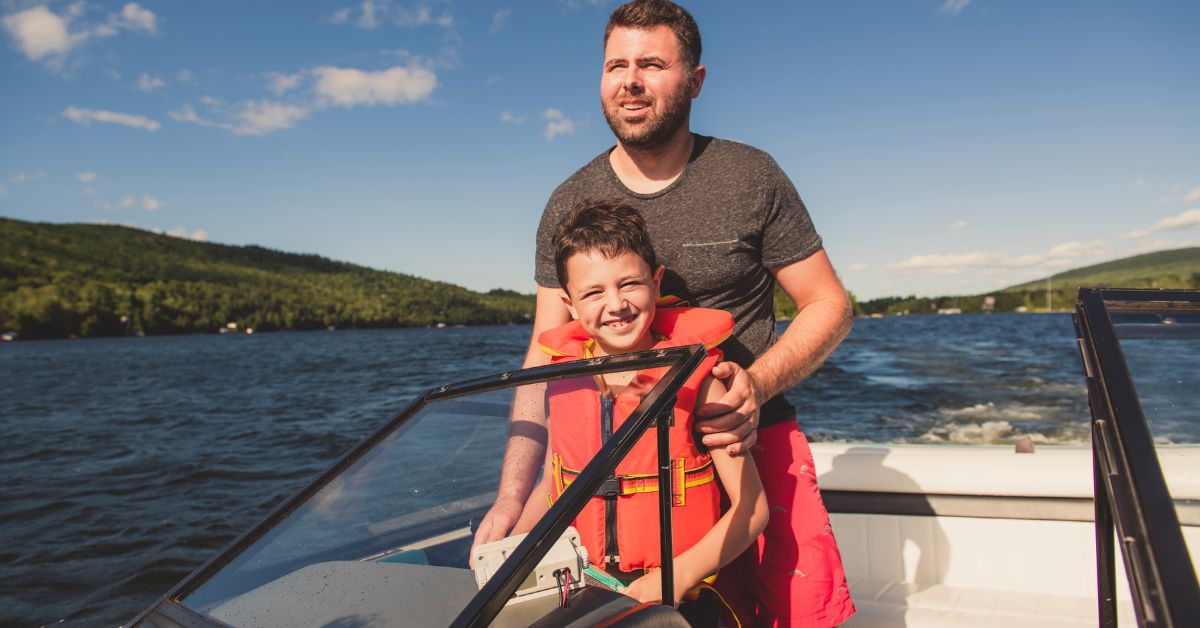 man standing behind his son on a boat on water
