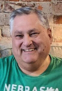 Headshot photo of Tim Trudell wearing a green shirt