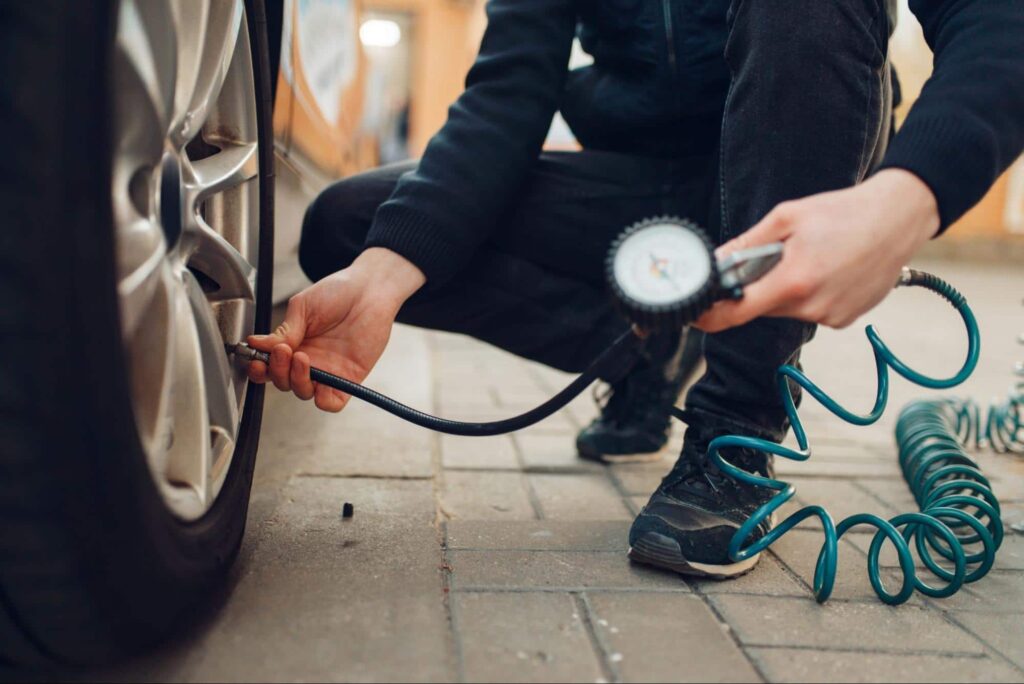 Someone checking a cars tire pressure