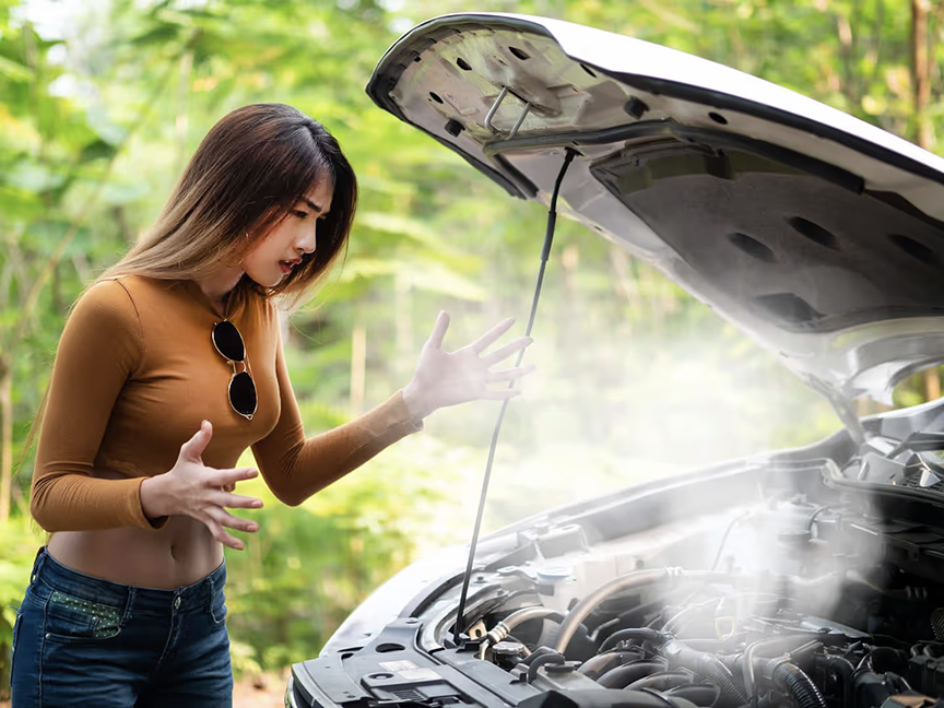 Woman standing in front of car with hood up and engine overheating