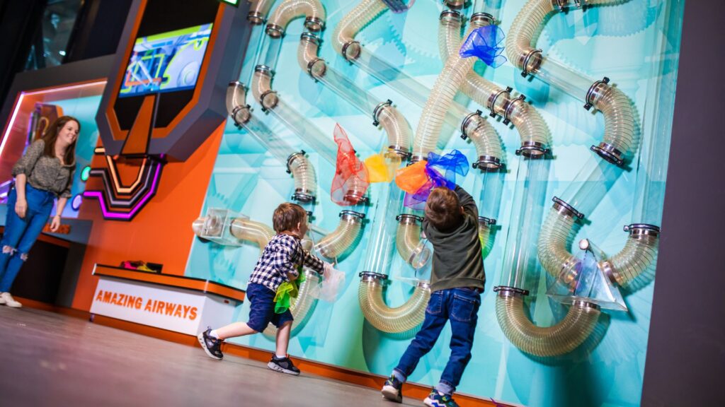 Kids examining a light blue display wall in a science center