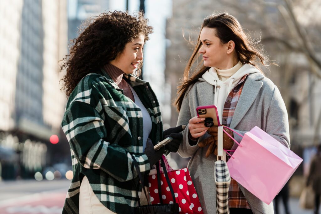two ladies in coats holiday shopping with pink and red shopping bags