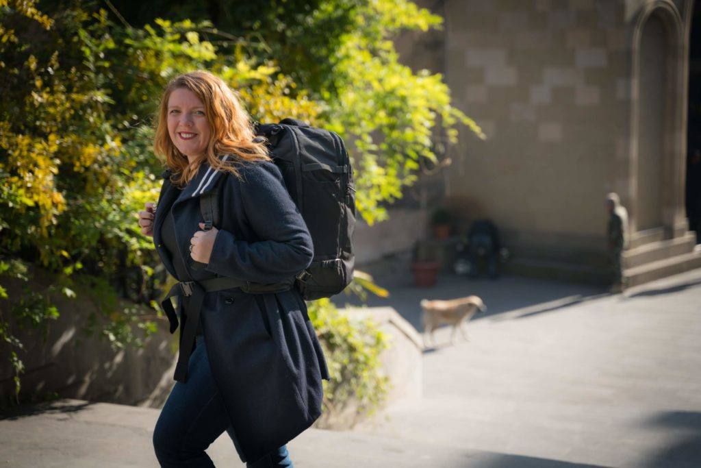 Lady dressed in black walking with a black backpack 