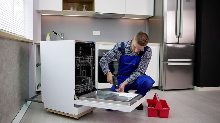 man fixing an automatic dishwasher in a kitchen