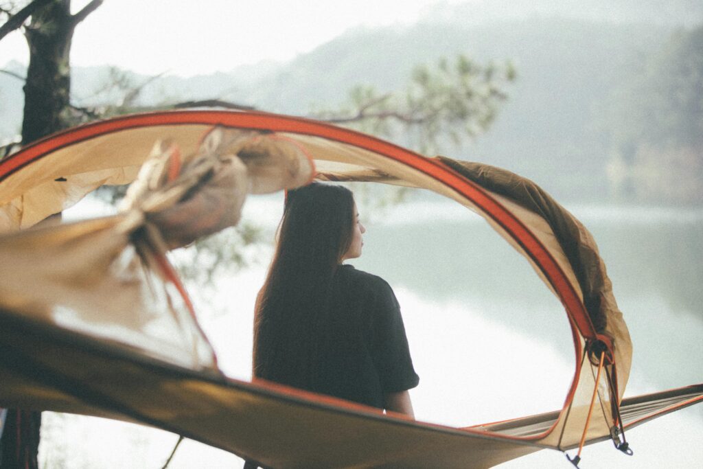 A woman with long dark hair sitting on a hammock with a cover