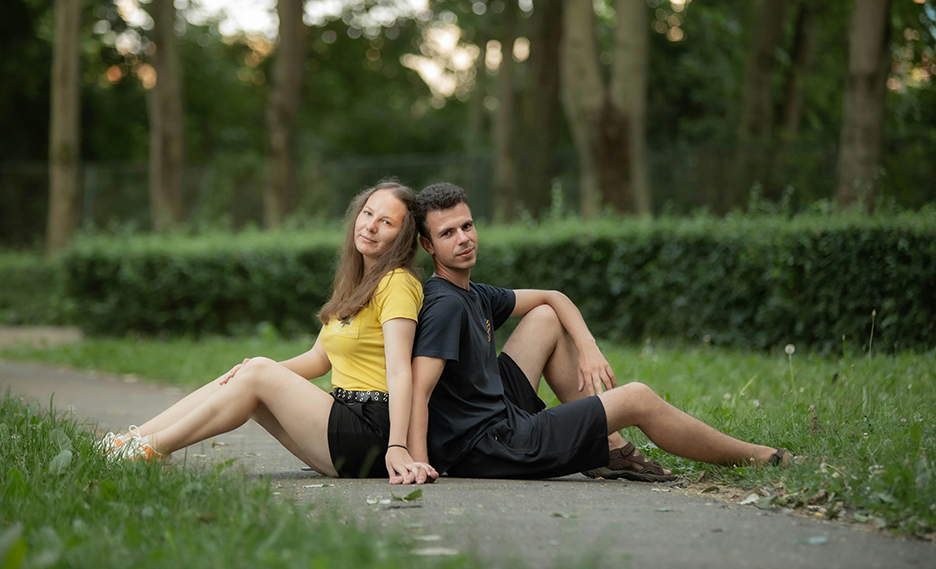 couple sitting on a sidewallk back to back