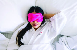 Someone in bed wearing a pink eye mask