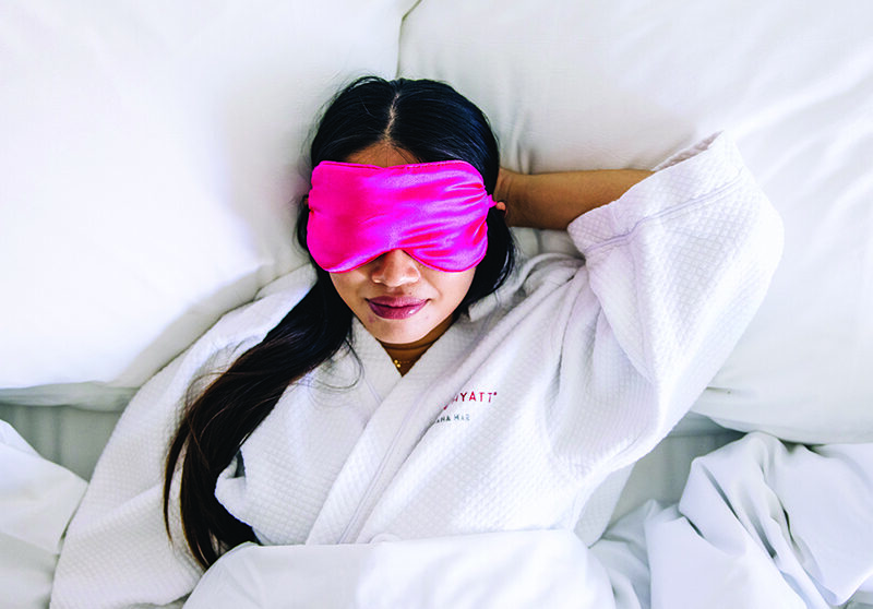 Someone in bed wearing a pink eye mask