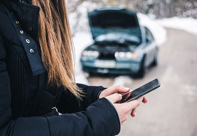 car in winter snow at side of road with hood up
