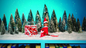 Toy elf sitting by a jar of candy