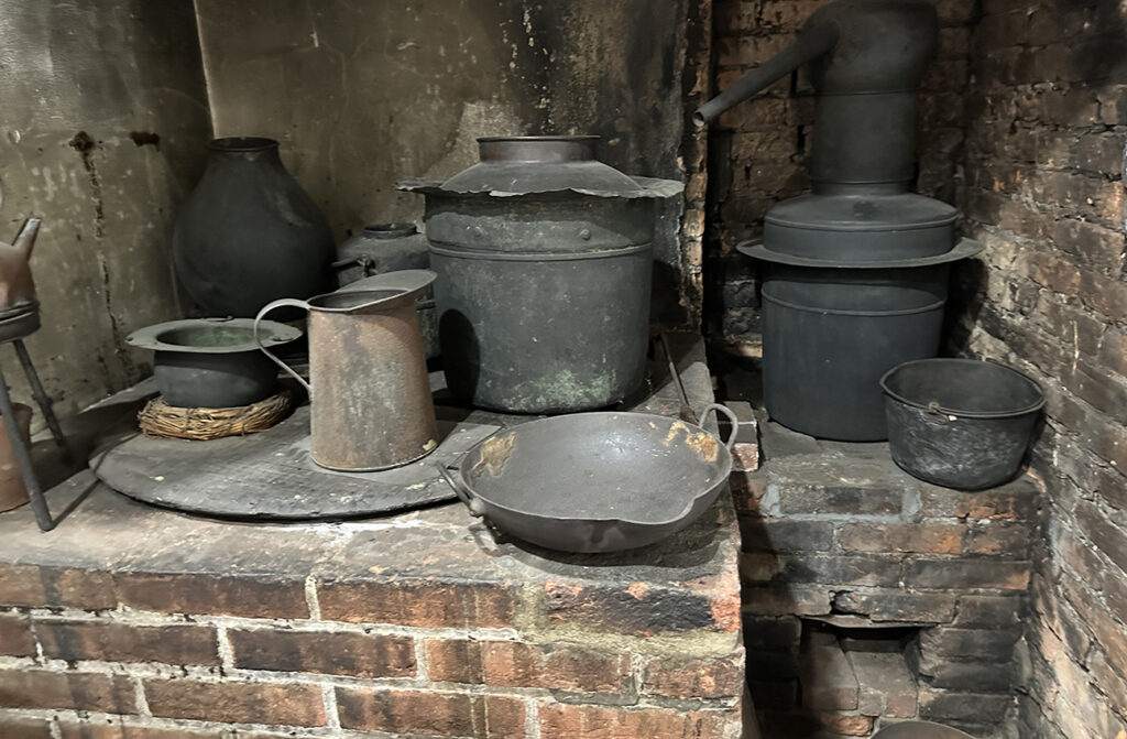 Black iron pots and pans sitting on a primitive brick kitchen counter