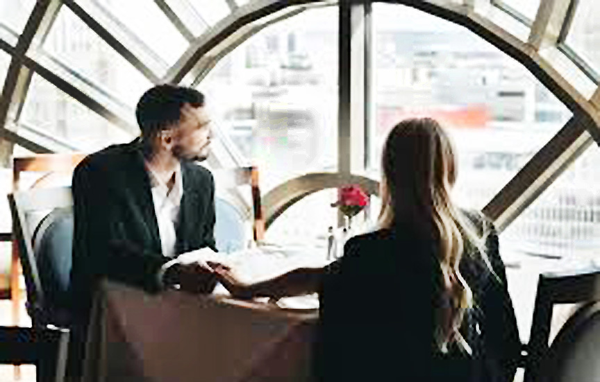 A couple at a restaurant looking at the city view out the window