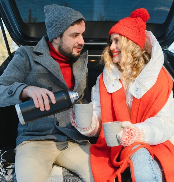 A Couple sitting together in the sharing a drink in the back of a car