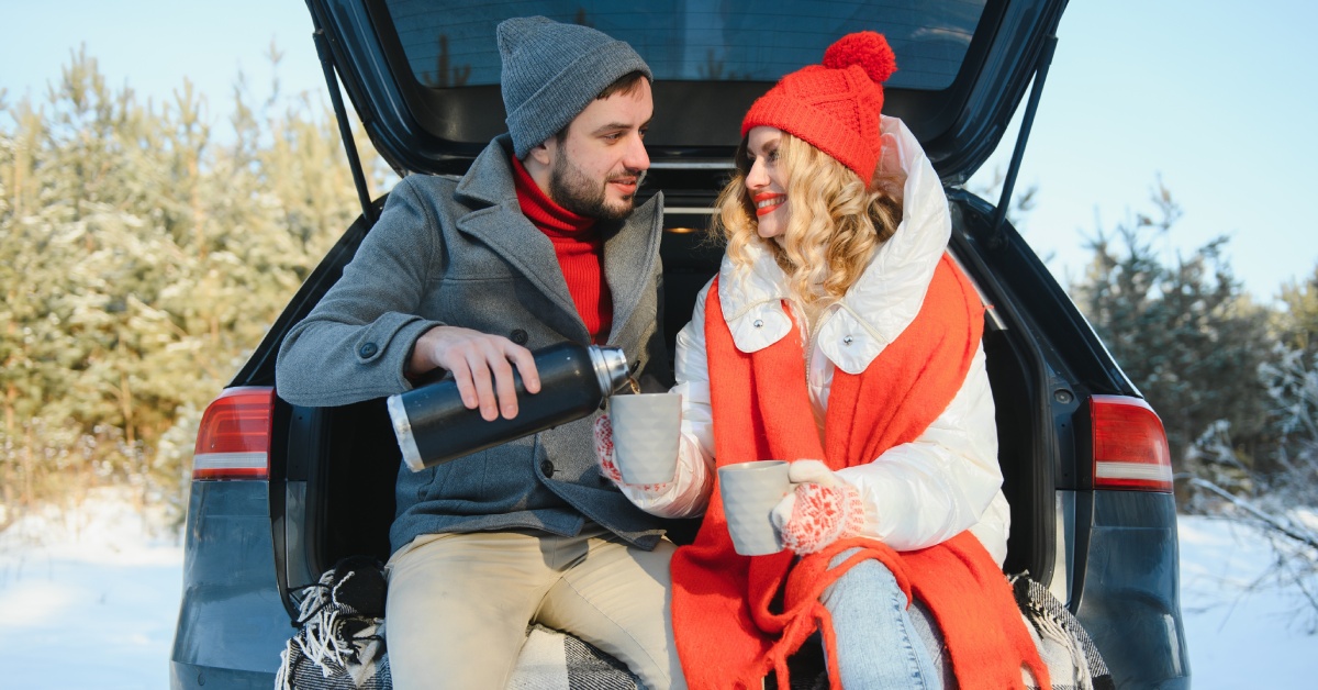 A Couple sitting together in the sharing a drink in the back of a car