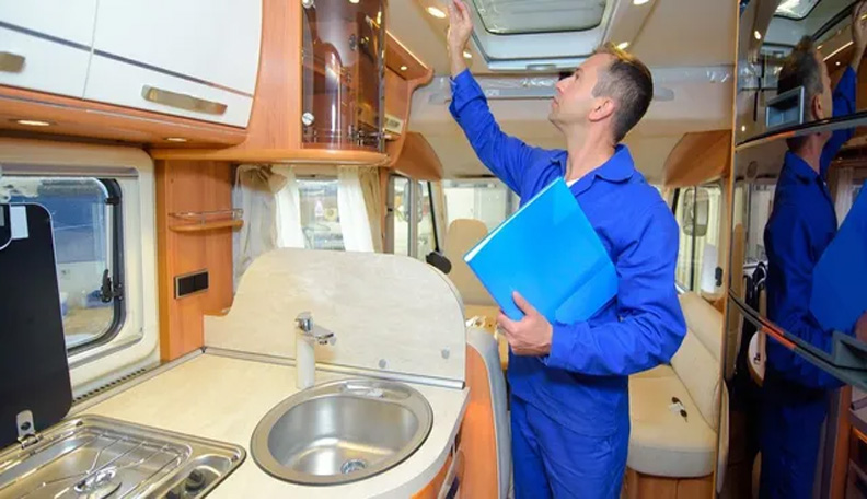 Man in lbue uniform and manual examining the inside of an RV