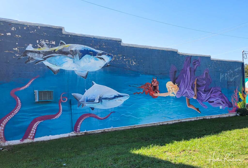 a mural with a mermaid and two fishes painted on it in a cartoony fashion 