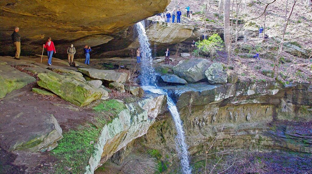 A waterfall in the center with rocks and greenery surrounding it