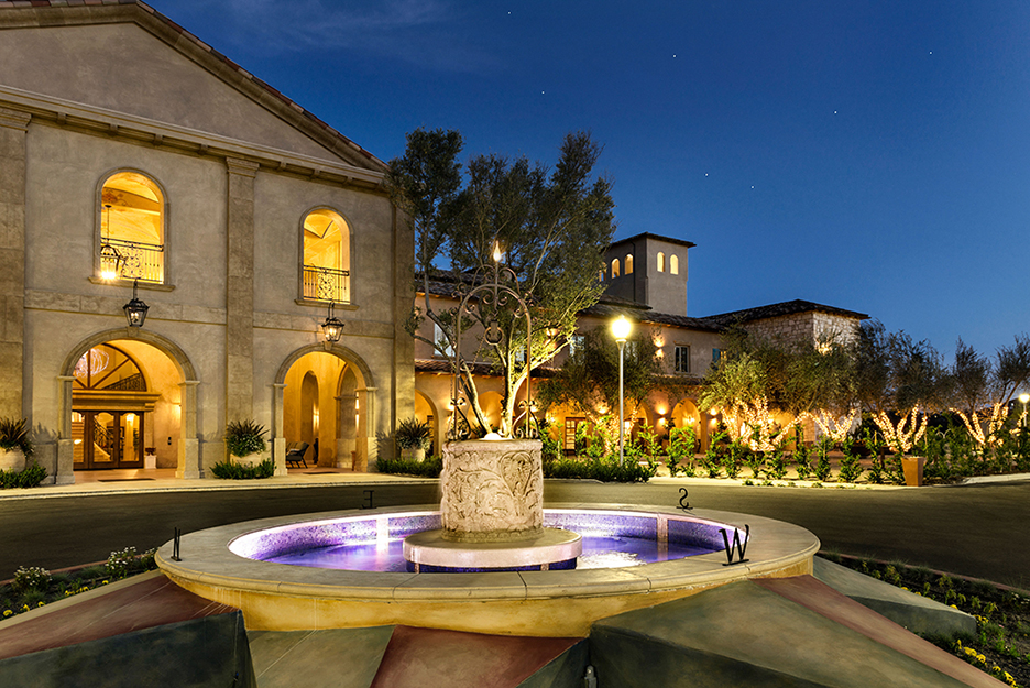 round fountain n front loawn of a two-story resort hotel at night with lights on