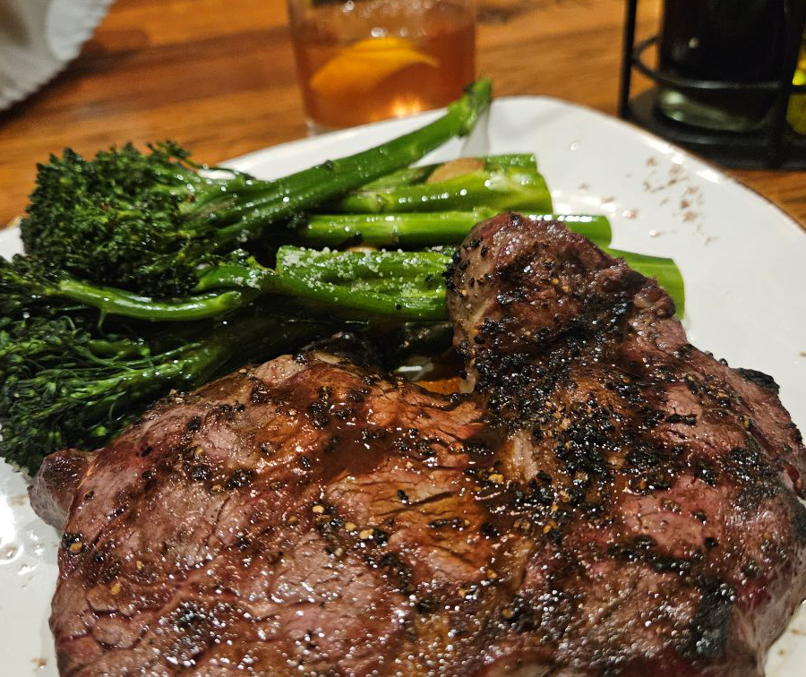 A plate of steak and broccoli garnished beside it