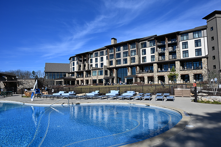 two story flat-top hotel resort with clear blue pool in the front