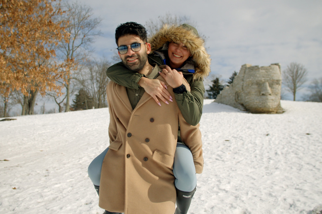 A man carrying a woman piggy-back in th snow 