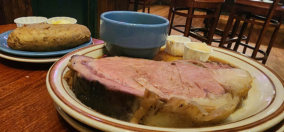 a thick steak of prime rib on a plate with a baked potato