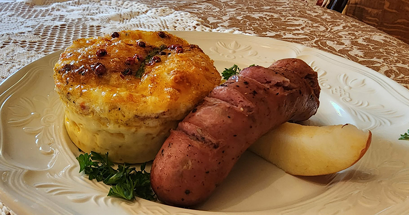 a sausage and souffle placed on a white plate on the breakfast table