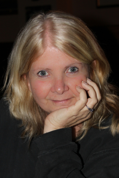headshot of a blonde lady restig her chin on palm of her hand